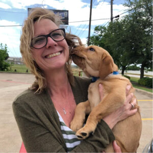 Cheryl holds Sully while she licks the side of Cheryl's face.