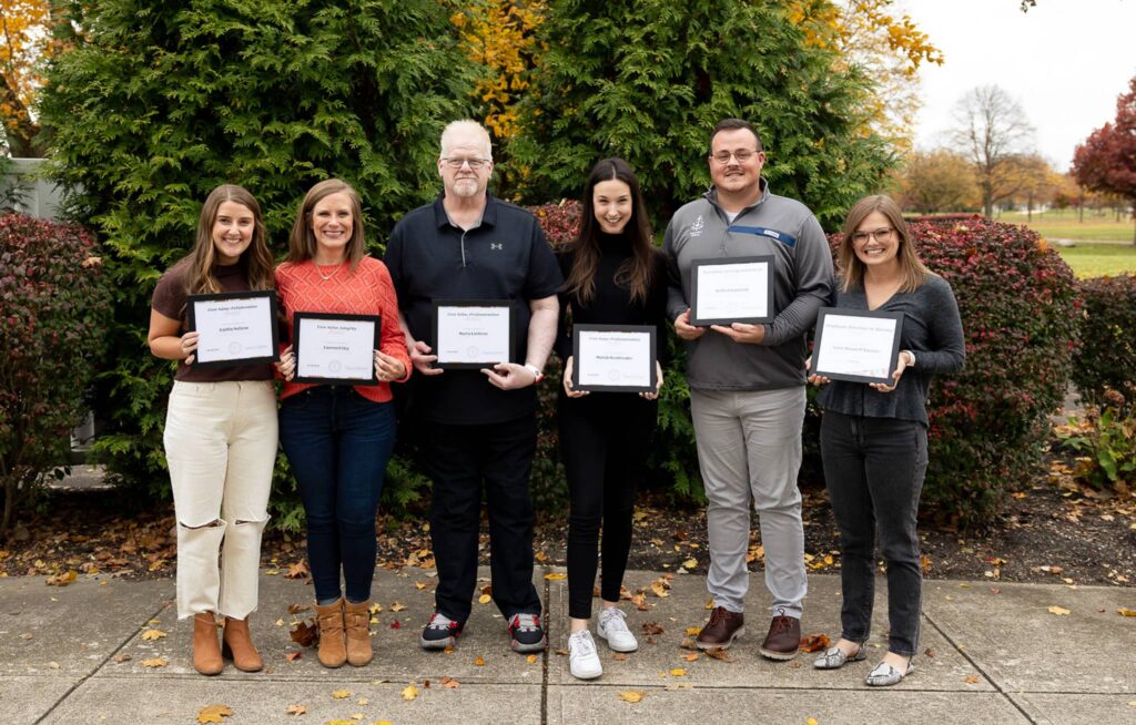 Six people holding up certificates