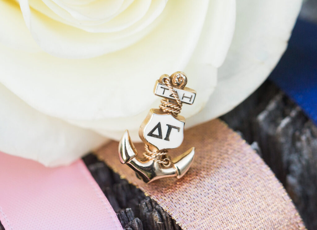 Delta Gamma pin over a white flower and pink ribbon