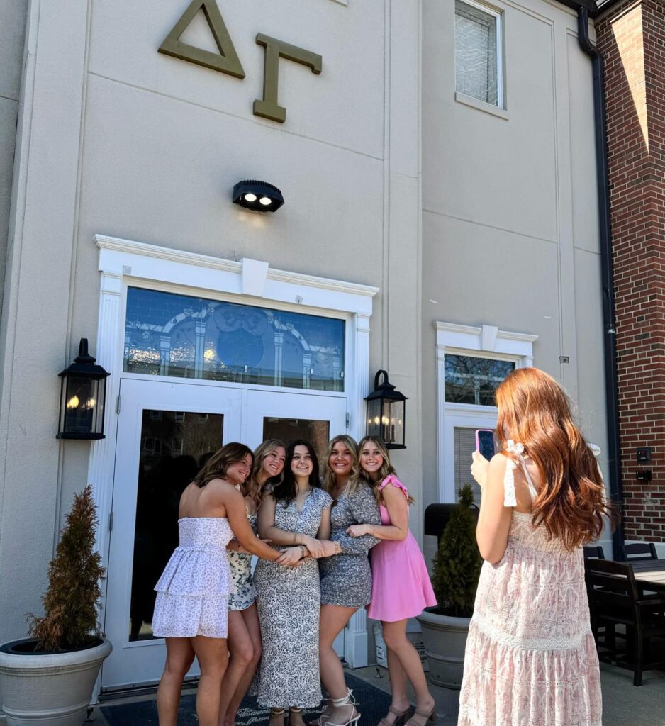 Delta Gamma sisters posing in front of a fraternity house