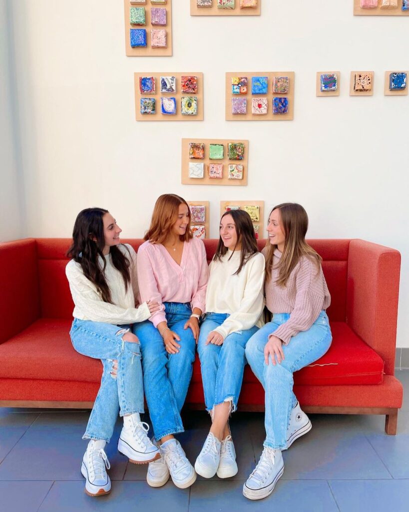 A group of four girls sitting on a red sofa