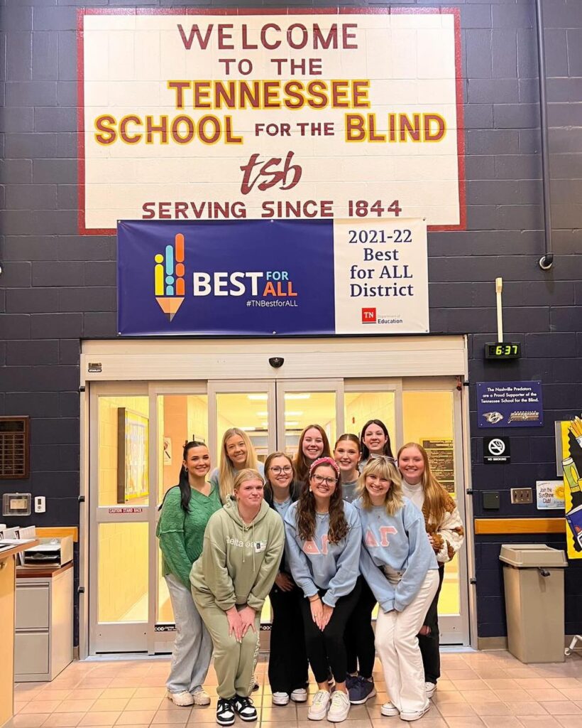 A group of girls posing in front of a school for the blind