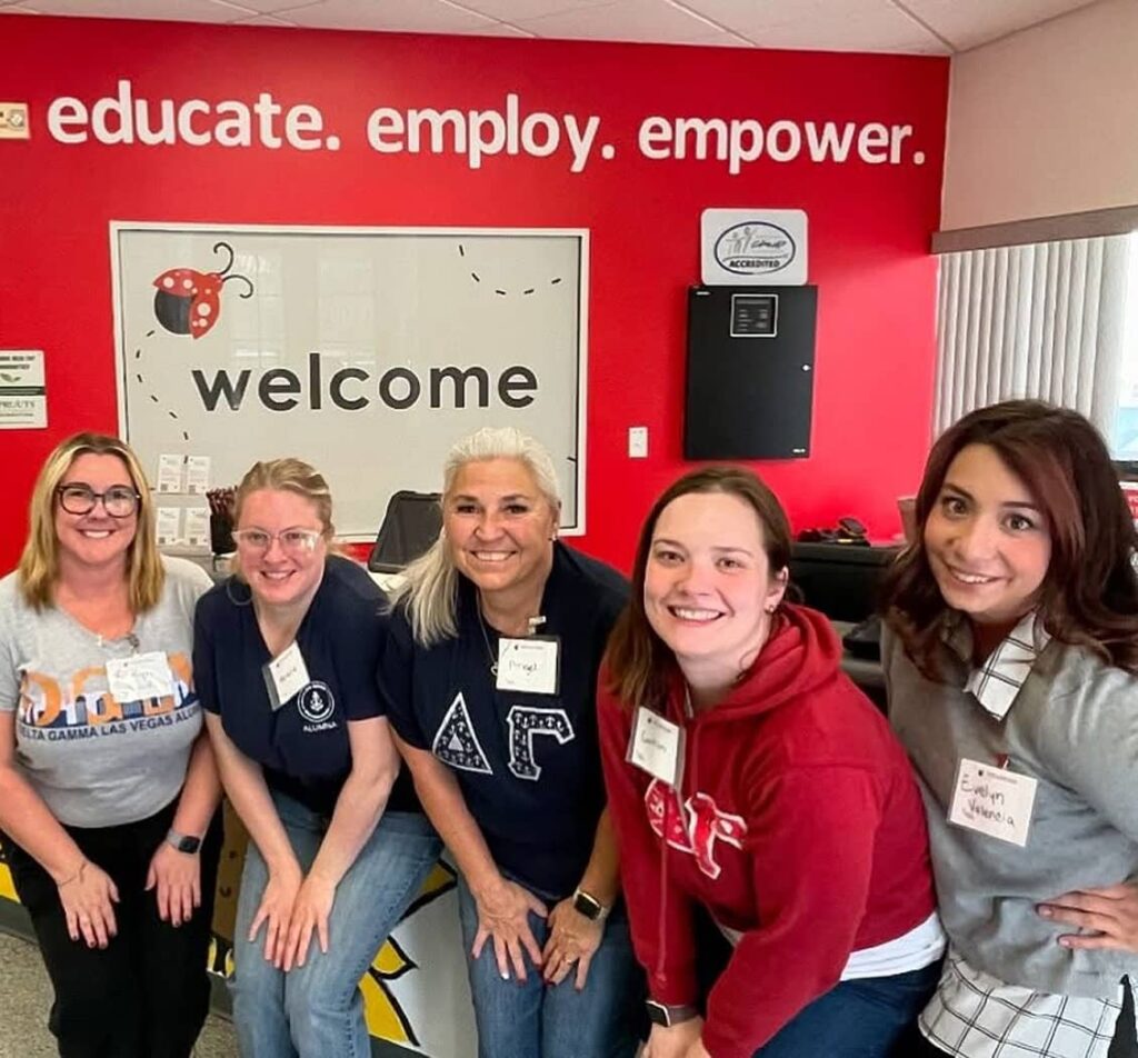Alumnae members squatting in front of red wall
