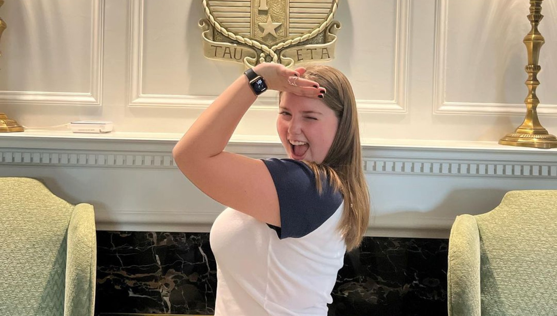 Girl doing the Delta Gamma sign indoors