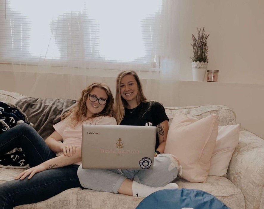 Two girls sitting on bed with laptop