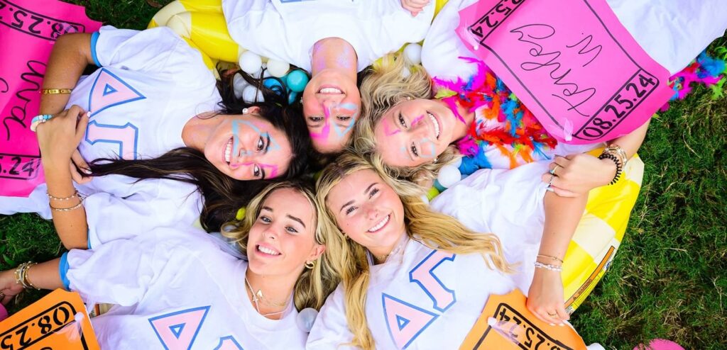 Group of Delta Gamma members laying on grass in a star like position looking up at camera
