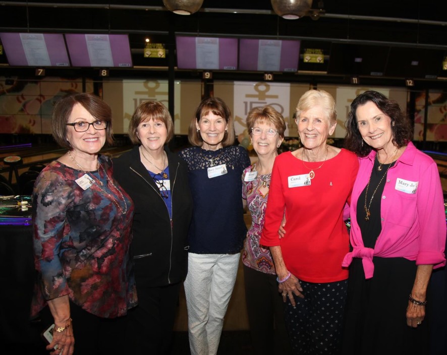 Alumnae members taking a photo in front of event