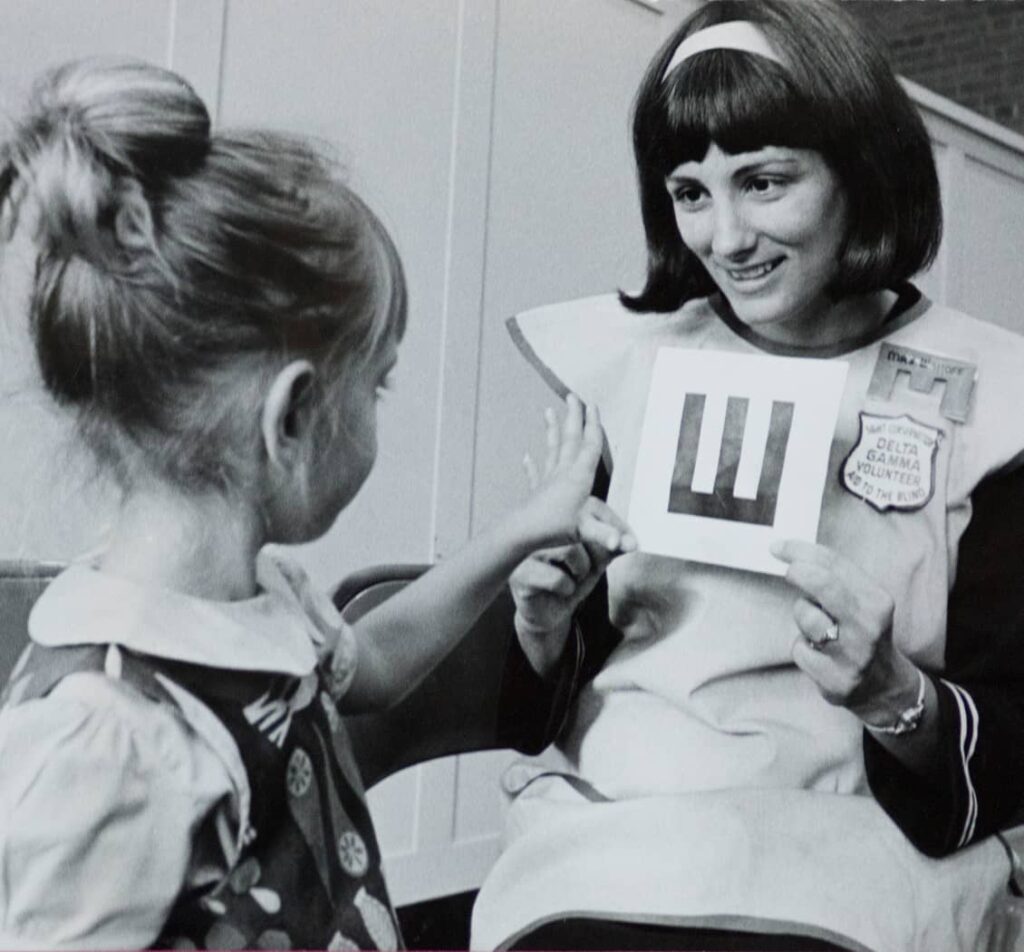 Two young girls learning. One girl holding up a letter.