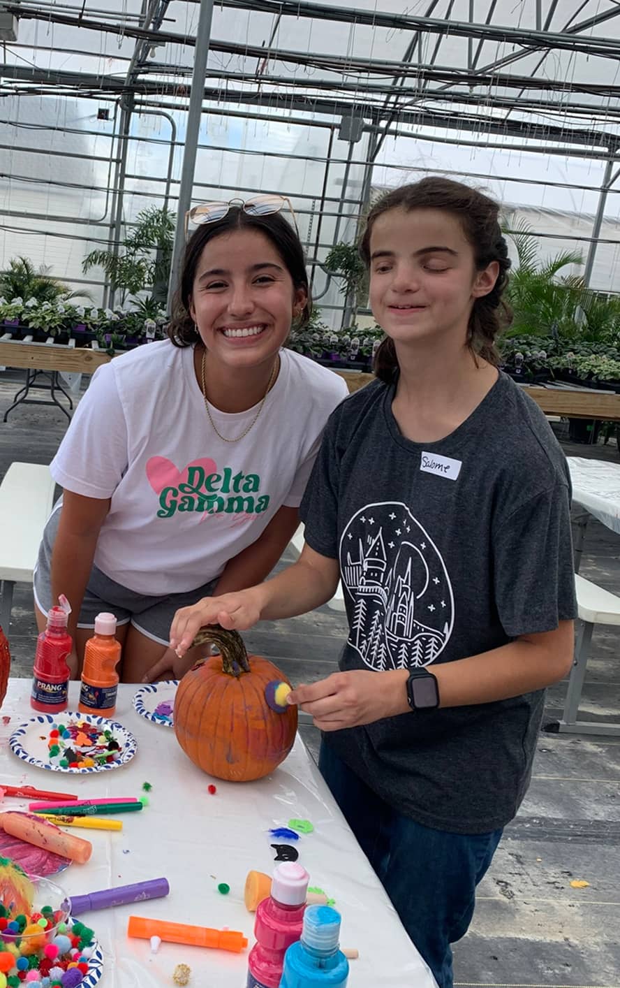 Delta Gamma member with young girl painting pumpkins