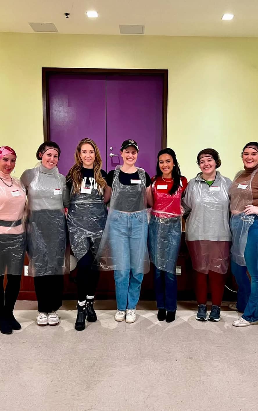A group of women standing with clear aprons and hair nets