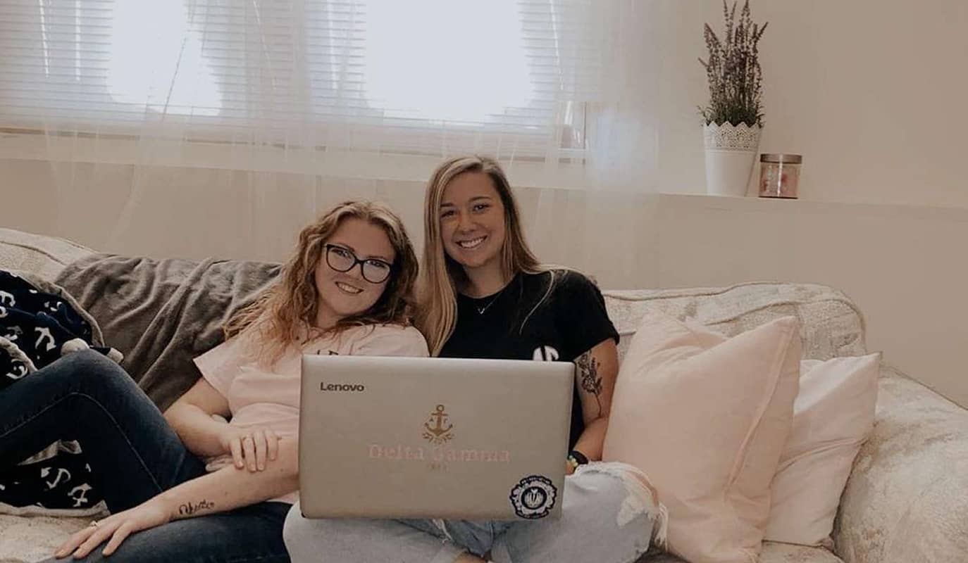 Two girls sitting on bed with laptop