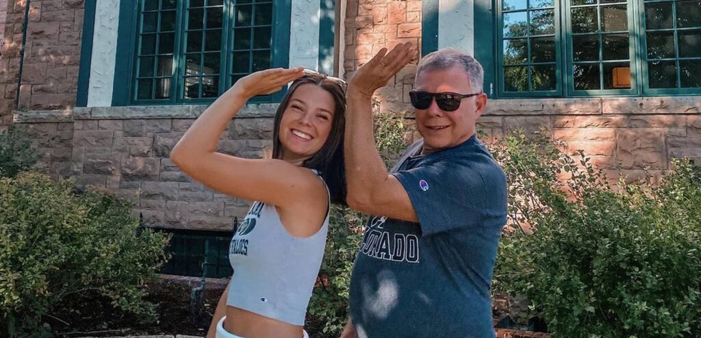 Daughter and Dad doing the Delta Gamma sign in front of house