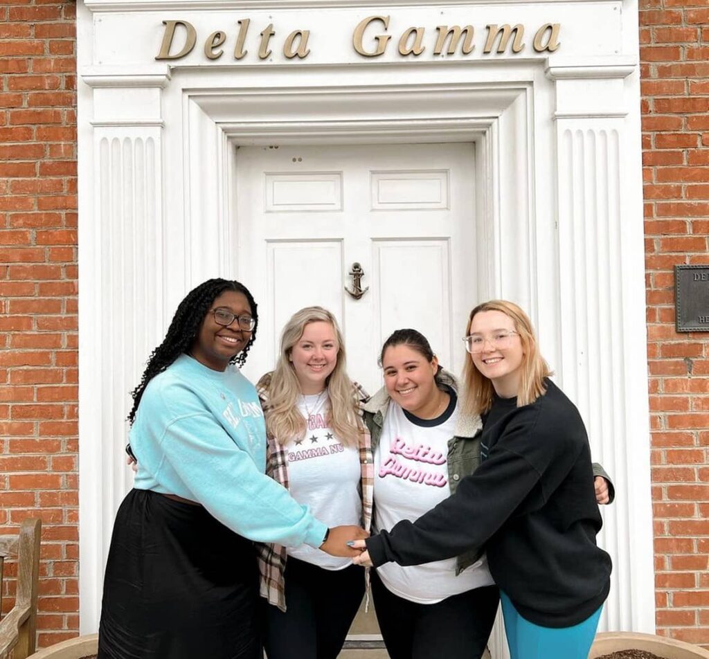 Group of Delta Gamma member holding hands in front of DG house