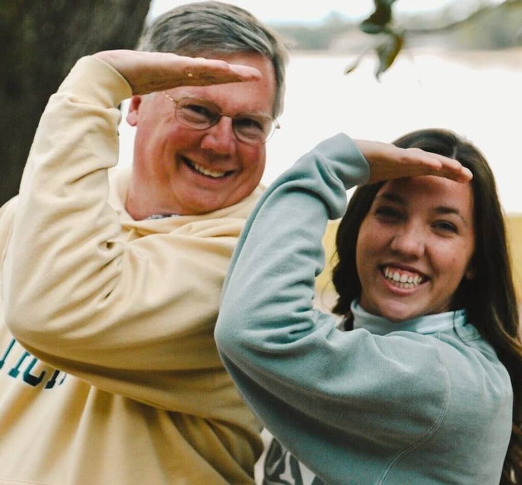 Daughter and Dad doing the Delta Gamma sign in front of lake