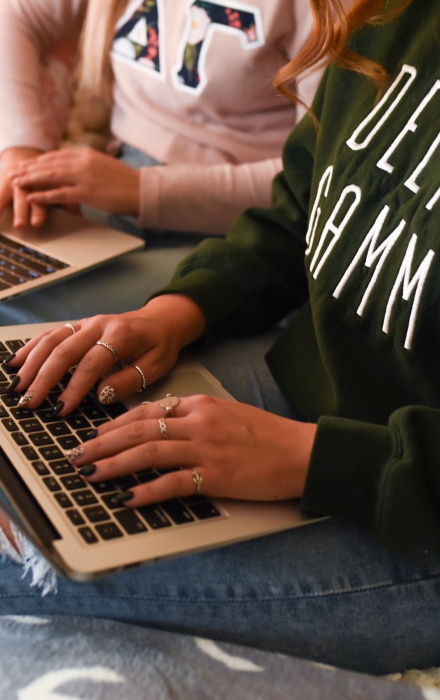 Girls on computers with Delta Gamma sweatshirts on.