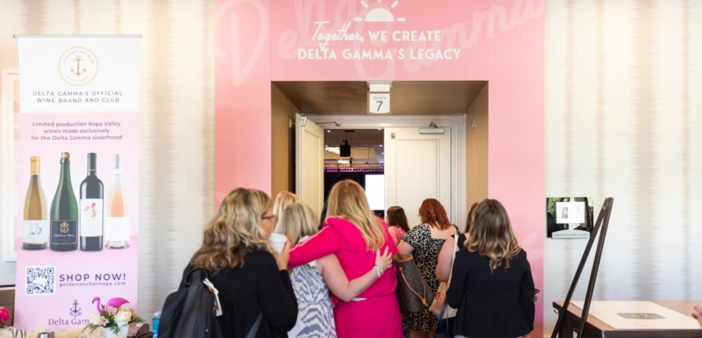 Group of women walking into convention of pink door frame way