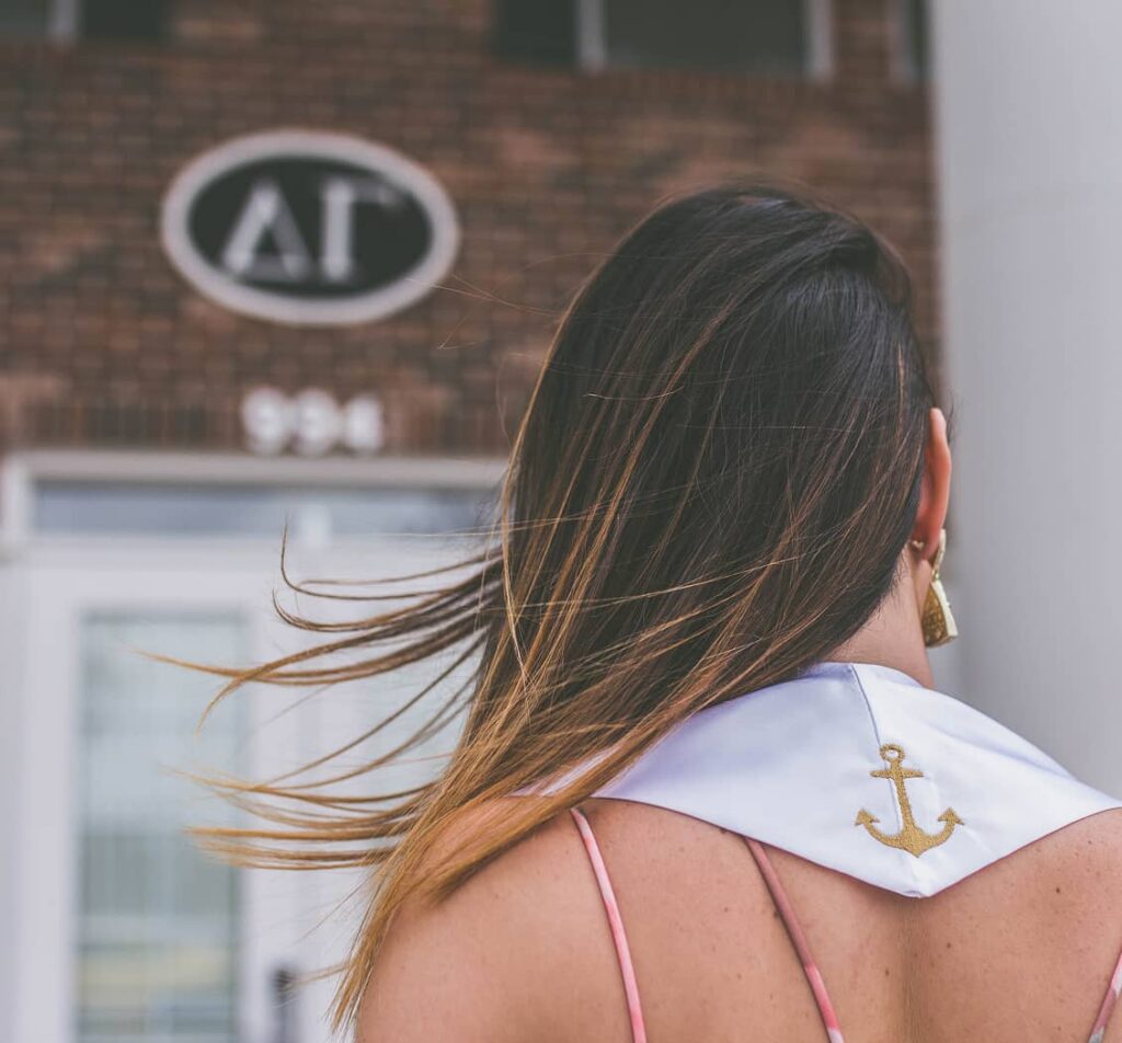 Girl wearing stoll on with anchor on back looking at DG house.