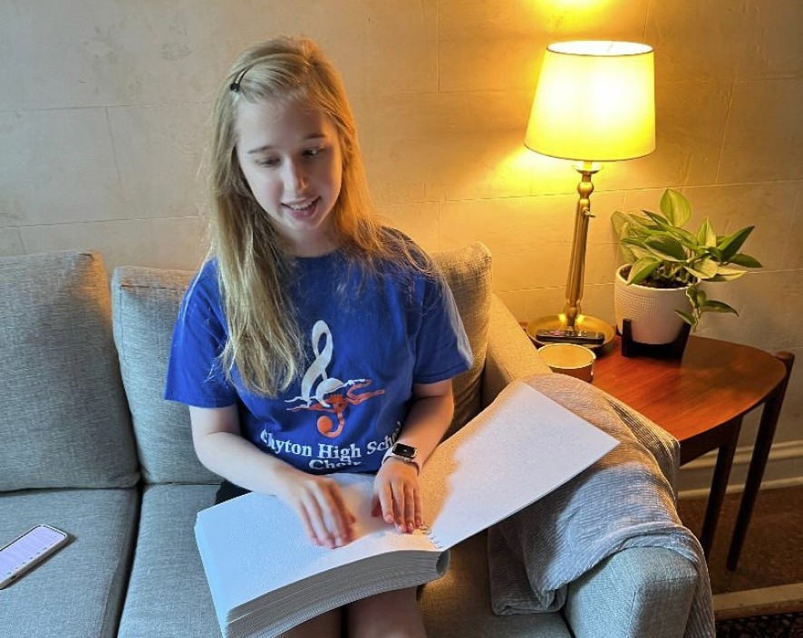 Young girl reading a book with braille