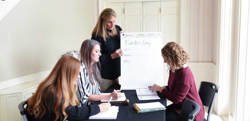 Women planning on founders day event with large sheet pad