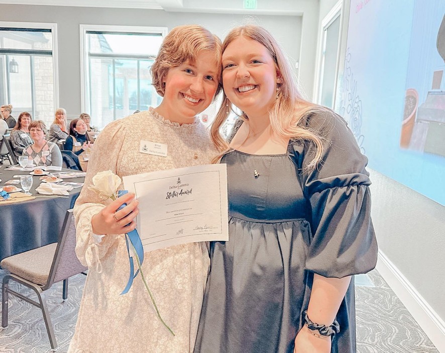 Two Delta Gamma Alumnae holding up DG paper