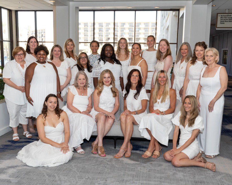 Group of Delta Gamma Alumnae all in white posing for a picture. (some standing some sitting)