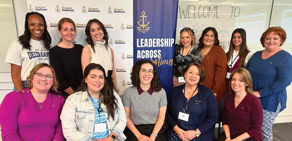 12 alumnae pose in front of a banner that says 