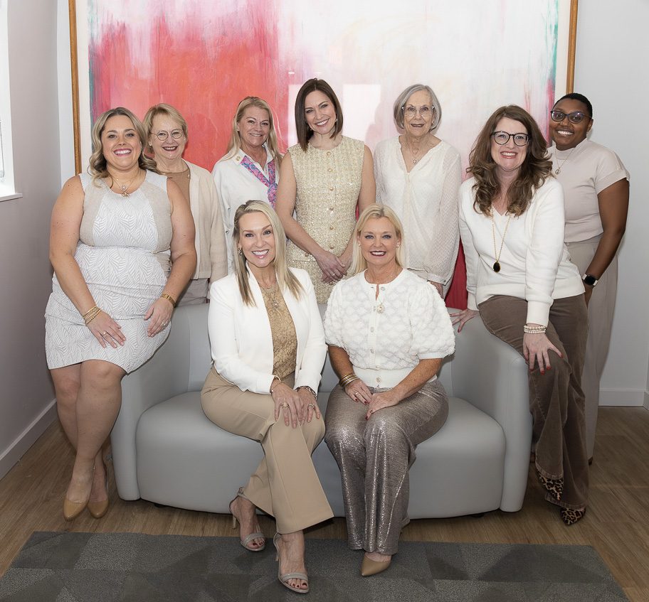 Nine BOT members pose inside in front of a large colorful abstract painting.