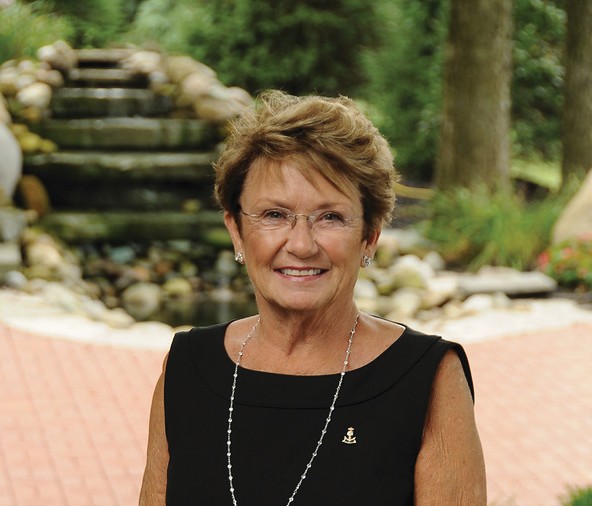 A member stands in front of a fountain outside. She is wearing her Delt Gamma badge.