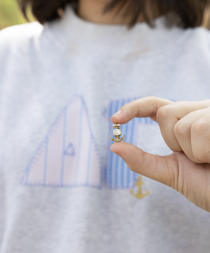 A sister holding a Delta Gamma badge.